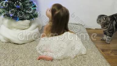 一个小<strong>女孩和</strong>一只猫正在<strong>圣诞树</strong>旁的房间里玩耍。 快乐的童年概念。 儿童<strong>和圣诞树</strong>